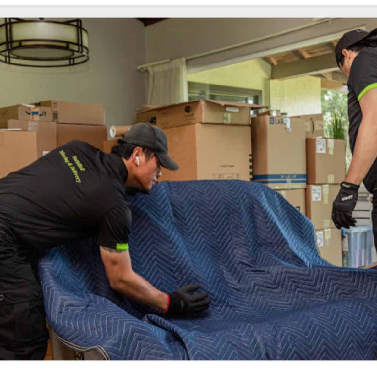 Movers wrapping a sofa in moving pads